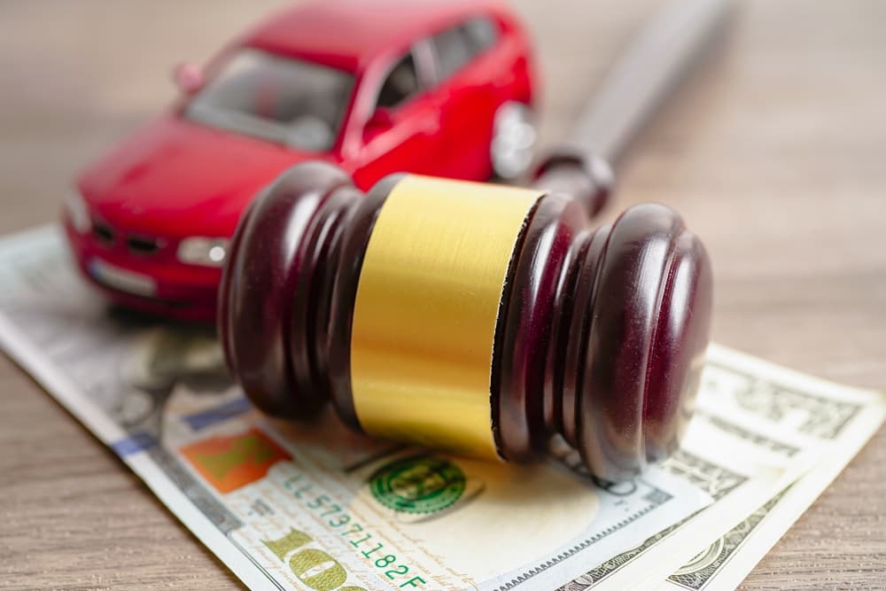 Judge's gavel with a car on US dollar banknotes, representing car loans, finance, savings, law, insurance, and leasing concepts.