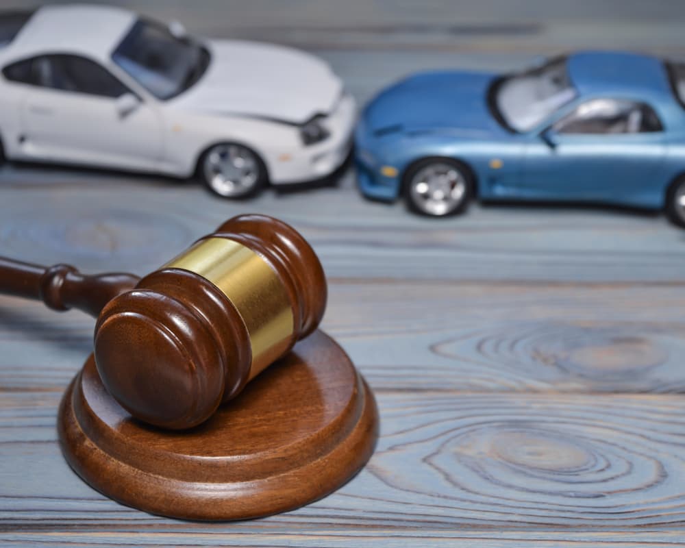 La imagen de un "martillo del juez" en el contexto de dos coches colisionados sugiere una escena de autoridad y consecuencia en medio de las secuelas de un accidente de coche. 