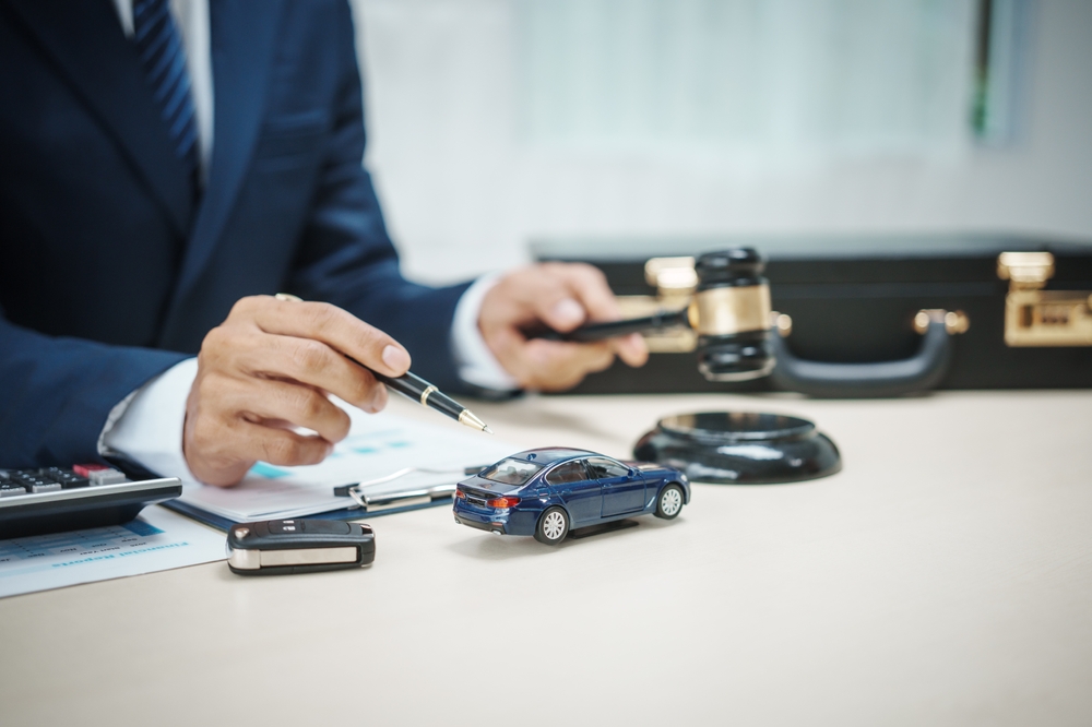 A man in a suit sells cars at his desk, offers online car insurance , car loans, comprehensive coverage, cash withdrawals via credit cards