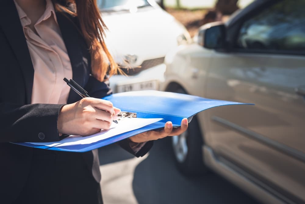 Mujer que denuncia un accidente de coche a los agentes de seguros, destacando los conceptos de seguro de personas y transporte.