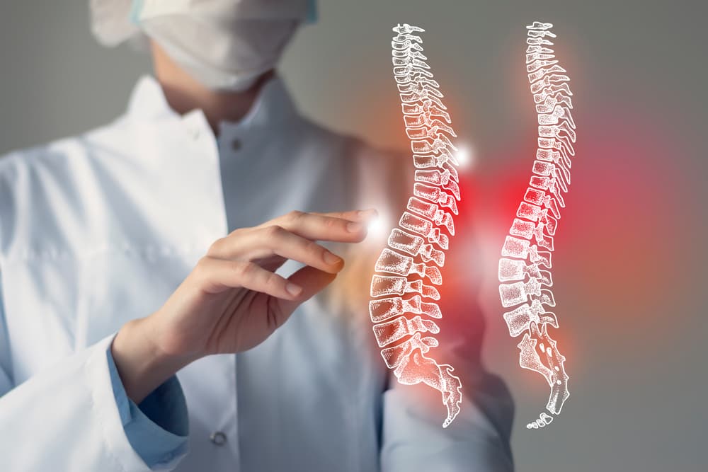 Una doctora examina un modelo virtual de columna vertebral, resaltando en rojo las zonas que le preocupan. Concepto de servicio sanitario y hospitalario.