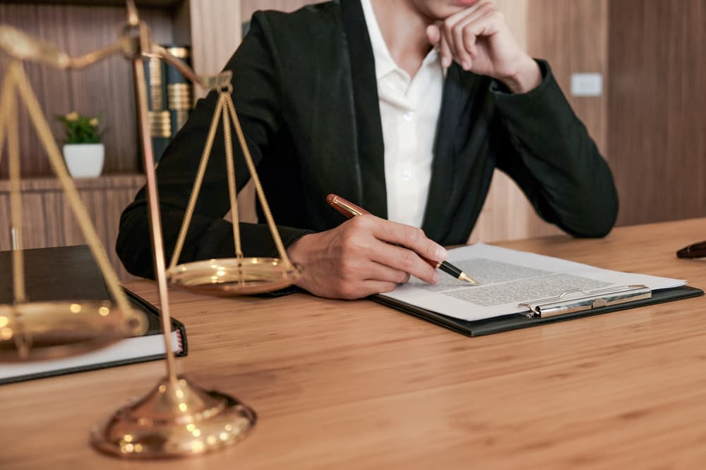 Legal counsel presenting a signed contract to a client with a gavel and legal documents on the table, symbolizing justice and the legal process.