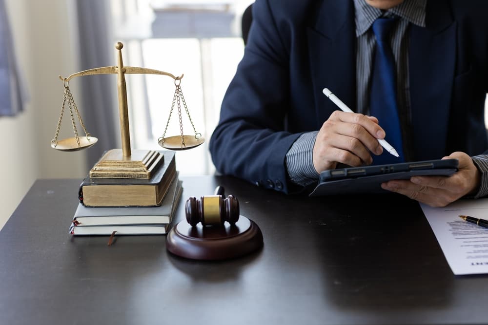 Lawyer's office with scales of justice and gavel, as the lawyer works on legal documents on a laptop, symbolizing the concept of justice