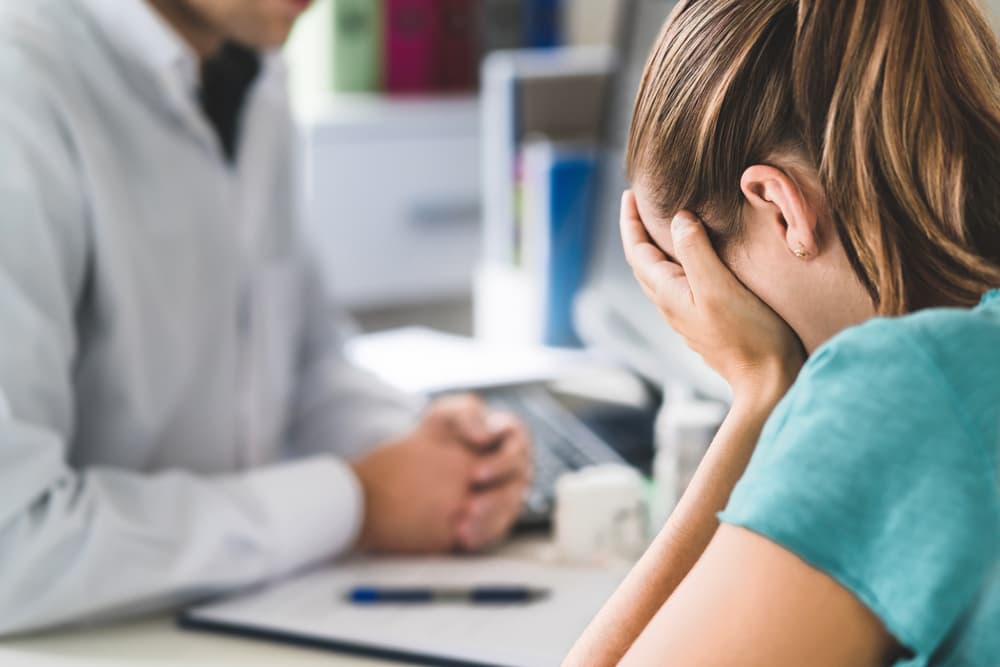 Una doctora consuela a una joven angustiada, ofreciéndole apoyo en caso de ansiedad o problemas de salud mental. Paciente recibiendo orientación médica y atención emocional.