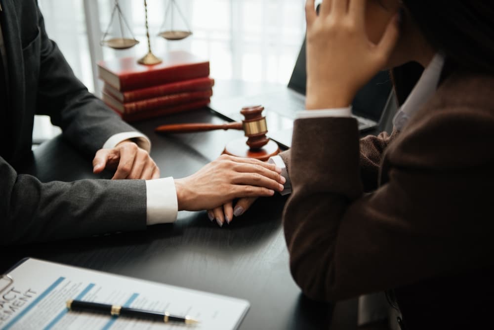 Personal injury lawyer leading a team meeting with clients at a law firm office, discussing legal matters.