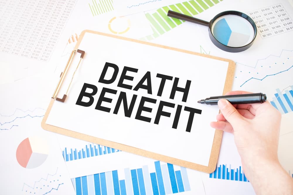 Businessman's hand holding a marker next to a sheet of white paper with the text 'DEATH BENEFIT' on top of a diagram.