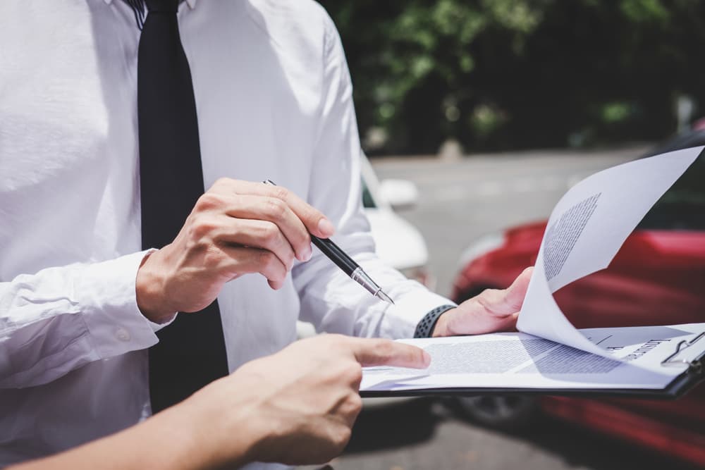 Agente de seguros tramitando informe de siniestro de accidente de coche, centrado en accidente de tráfico y concepto de seguro.