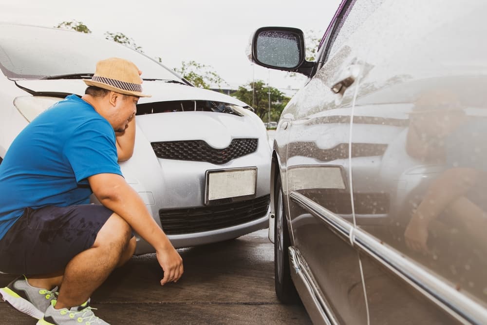 Man sits and watches the aftermath of a car crash caused by a speeding vehicle crossing lanes without following traffic rules on a highway: Accident insurance concept.