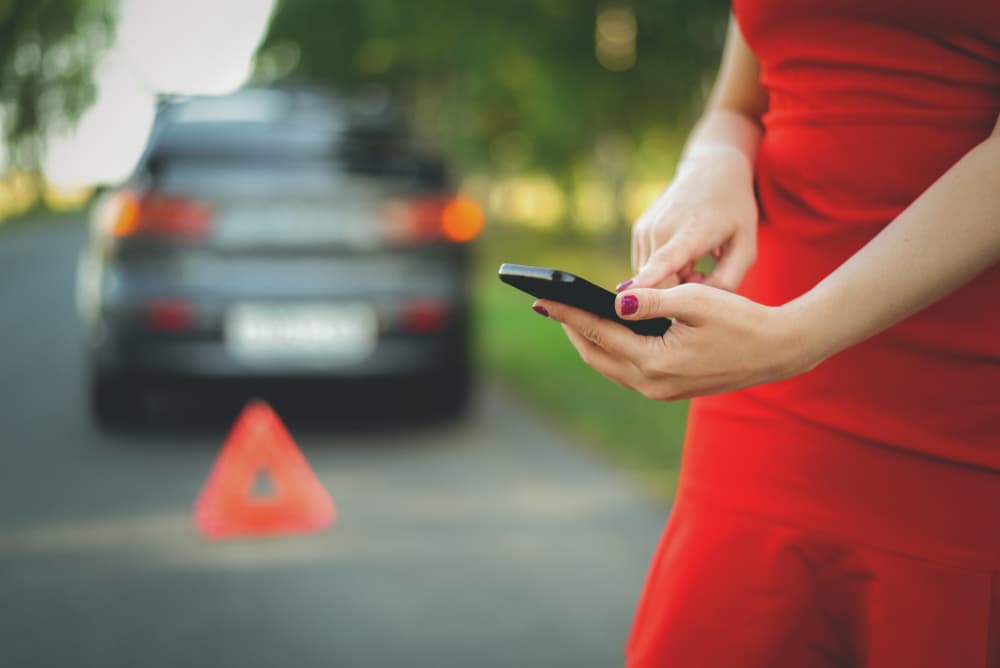 Woman calling for assistance on her mobile phone after a car accident.