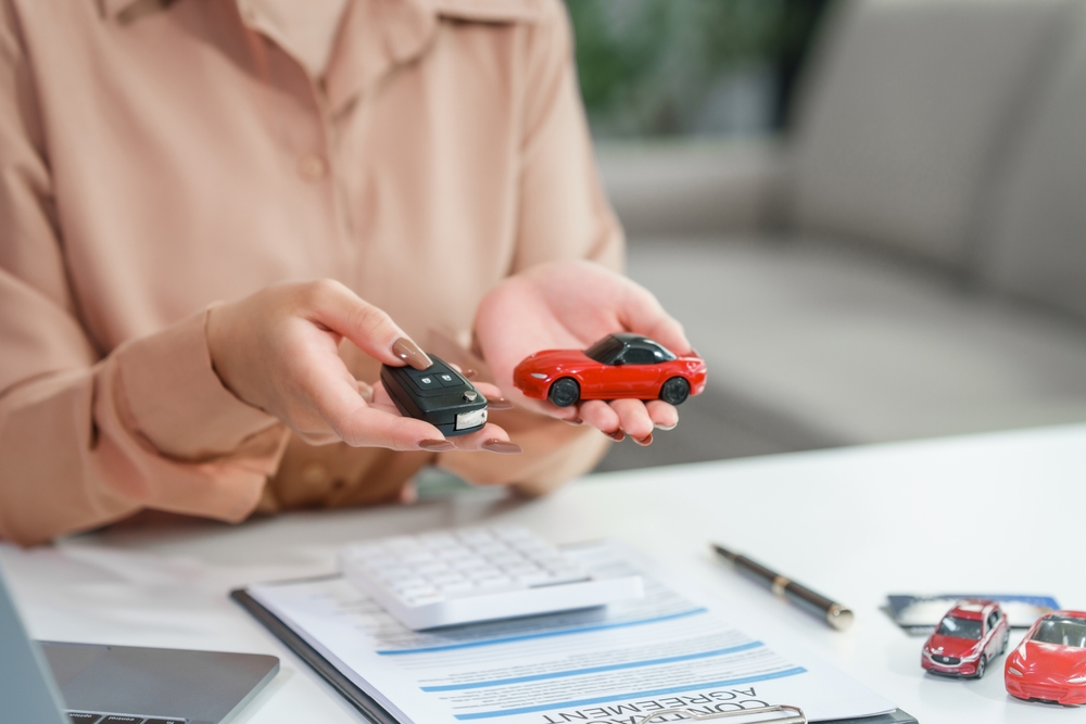 Asian businesswoman negotiating the sale of a car, discussing insurance and financing options, including used car loans, premiums, deductibles, and various coverage options.